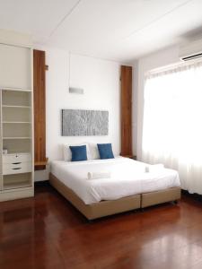 1 dormitorio con 1 cama blanca grande con almohadas azules en Cozy by Funwahn, en Chiang Mai