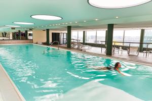 a woman swimming in a pool in a building at Steigenberger Airport Hotel Frankfurt in Frankfurt/Main