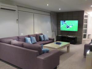 a living room with a couch and a flat screen tv at Bella Seven- Waiheke Escapes in Oneroa