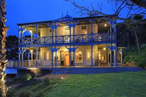 a large white house with a large deck at The Sanctuary- Stay Waiheke in Oneroa