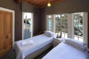 two beds in a room with two windows at The Sanctuary- Stay Waiheke in Oneroa