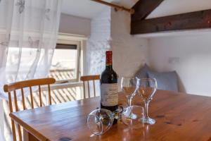 Una botella de vino sentada en una mesa de madera con copas en Crew's Apartment en Dungarvan