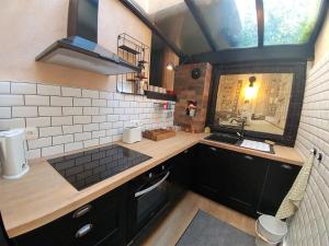 a kitchen with black cabinets and a sink and a window at MAISON JARDIN ET PARKING PRIVé dans GRENOBLE in Grenoble