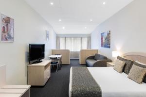 a hotel room with a bed and a flat screen tv at Adelaide Granada Motor Inn in Adelaide