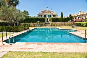 a swimming pool in front of a house at The Fairway Vista, Your Luxury Retreat with a Quiet Pool in Pueblo Nuevo de Guadiaro