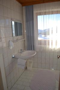 La salle de bains blanche est pourvue d'un lavabo et d'une fenêtre. dans l'établissement Innviertler Berggasthof, à Radstadt