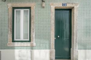 two green doors on the side of a building at Madragoa Studios in Lisbon