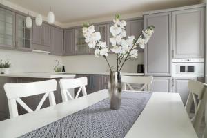 eine weiße Küche mit einem Tisch und einer Vase aus Blumen in der Unterkunft CASA VERDE Apartment in Bratislava