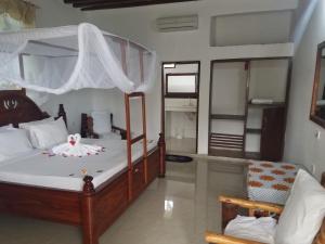 a bedroom with a canopy bed and a chair at Baraka Beach Bungalows in Nungwi