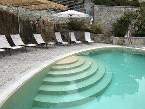 a swimming pool with chairs and an umbrella at Mergozzo Beach in Mergozzo