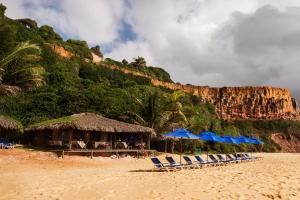 a group of chairs and umbrellas on a beach at Hotel Ponta do Madeiro in Pipa