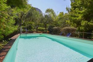 a swimming pool with blue chairs and trees at Villa Majus in Porticello