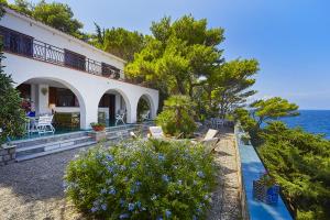 a house with chairs and the ocean in the background at Villa Majus in Porticello