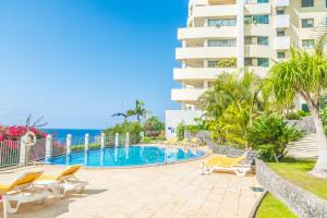 a swimming pool with chairs and a building at Arcadas Grand Sea View in Funchal