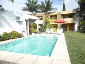 a pool in front of a house with chairs and an umbrella at Las Balsas Hotel in Federación