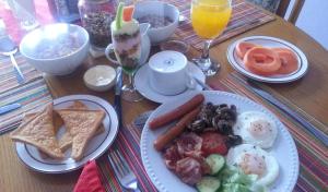 a wooden table topped with plates of breakfast food at Ekhaya Lodge in Pietermaritzburg