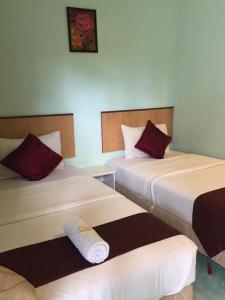 a hotel room with two beds with red pillows at Rose Inn Motel in Kuah