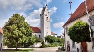 a white church with a clock tower on a street at FerienwohnungenAufDemDorf nahe LEGOLAND in Neuburg an der Kammel