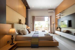 a bedroom with a large bed and a tv at Villa Melasti Wardana in Uluwatu