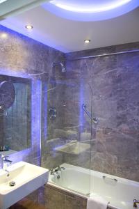 a bathroom with a tub, sink, and mirror at Cork's Vienna Woods Hotel & Villas in Cork