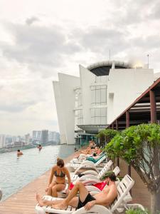 a group of people sitting on lounge chairs in the water at T1 KLCC view Studio@Regalia Infinity Pool in Kuala Lumpur
