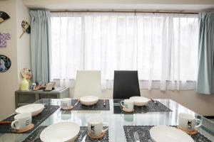 a dining room with a glass table with bowls and mugs at Station Condominium Otsuka in Tokyo