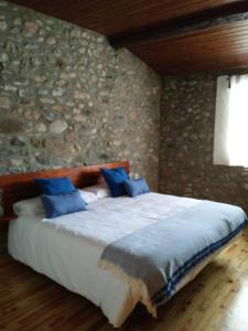 a bed in a room with a stone wall at Hotel Cal rei de Talló in Bellver de Cerdanya