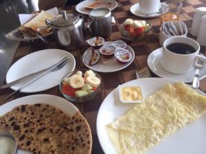 a table with plates of food and a cup of coffee at Hotel Mewar Haveli - At Lake Pichola in Udaipur