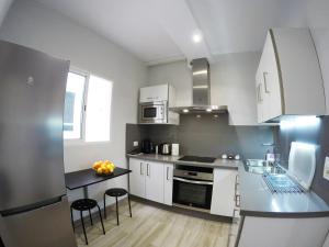 cocina con armarios blancos y encimera negra en Apartamentos Ainara en Santa Cruz de Tenerife