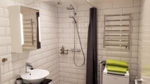 La salle de bains blanche est pourvue d'un lavabo et d'une douche. dans l'établissement PAX Apartments, à Lund