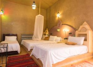 een slaapkamer met 2 bedden en witte lakens bij Riad Ouzine Merzouga in Merzouga