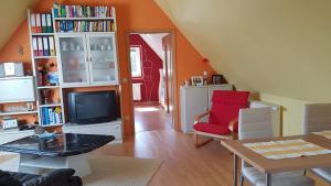- un salon avec une télévision et une chaise rouge dans l'établissement Ferienhaus Hildegard, à Muhr amSee