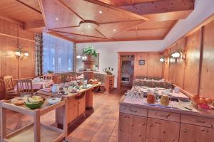 cocina grande con paredes de madera, mesas de madera y sillas en Pension Schusterkrämer en Maria Alm am Steinernen Meer