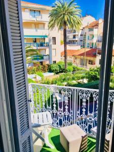 a balcony with a view of a palm tree and a building at Apartment 3 Pieces in Cannes