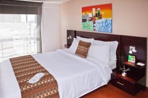 a bedroom with a large white bed with a large window at Aparta-Suites Mirador del Recuerdo in Bogotá