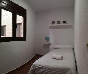 Cette petite chambre comprend 2 lits et une fenêtre. dans l'établissement Apartamentos nueva 13, à Ronda