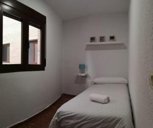 a small room with two beds and a window at Apartamentos nueva 13 in Ronda