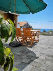 馬達萊娜的住宿－Casa do Sal，一张桌子和椅子,配有雨伞和大海