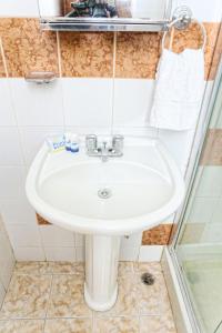 a bathroom with a white sink and a shower at Hotel Aluge in Santo Domingo