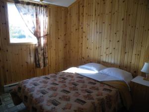 a bedroom with a bed with wooden walls and a window at Chalets Shipek in Les Escoumins