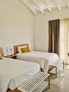 two beds in a white room with a window at Casa do Sal in Madalena