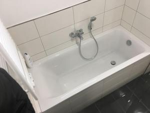 Zimmervermietung Hofmeister في هايلباد هايليغنشتات: حوض استحمام أبيض مع دش في الحمام