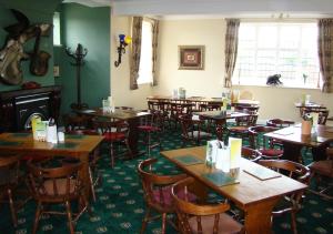 a dining room with tables and chairs and a fireplace at Bird In Hand in Henlow