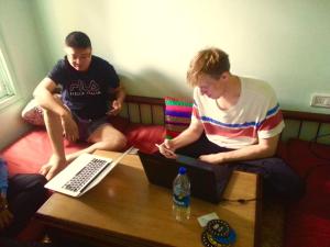 two men sitting on a couch with their laptops on a table at Hostel Mantra in Mumbai