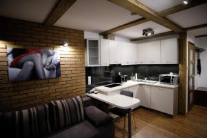 a kitchen with white cabinets and a brick wall at Apartamenty Wygoda Białystok in Białystok