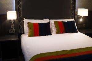 a bed with two colorful pillows and two lamps at Glenavon House Hotel in Cookstown