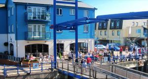 a group of people walking on a pier next to buildings at Summerwind Guest House in Exmouth