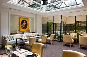 comedor con mesas y sillas y techo de cristal en Hôtel San Régis, en París