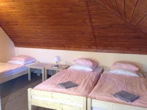 two beds in a room with a wooden ceiling at Park Vendégház in Kecskemét