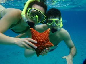 um homem segurando uma estrela-do-mar na água em Paraiso Beach Hotel em Big Corn Island